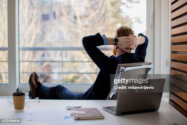 businessman sitting in the office and looking through the window - resting imagens e fotografias de stock