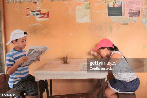 young boy and girl relaxing at local cafe. - zeitung lesen zwei personen stock-fotos und bilder