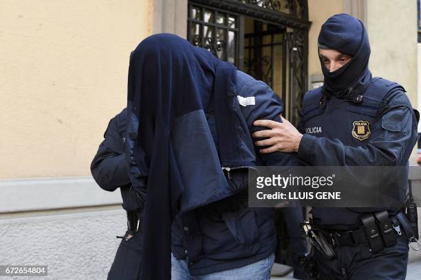 Members of the Catalan Regional Police arrest a man accused of collaborating with the Islamic militants, after searching a flat in Barcelona on April...