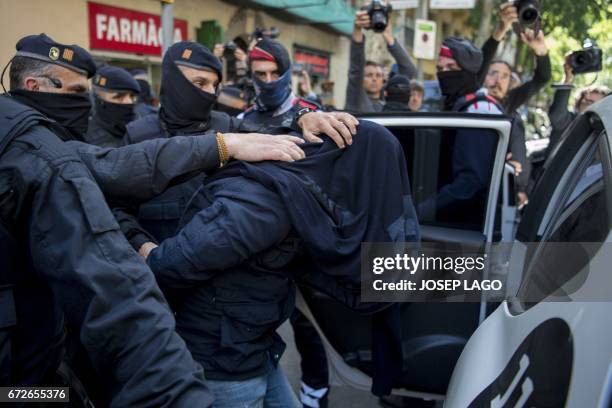 Members of the Catalan Regional Police arrest a man accused of collaborating with the Islamic militants, after searching a flat in Barcelona on April...