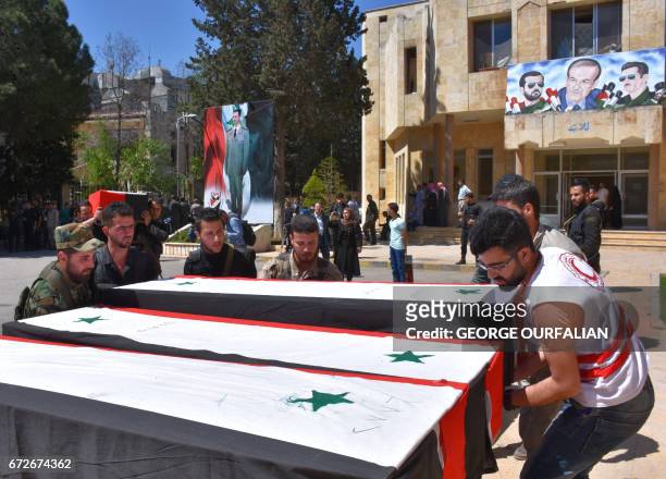 Syrians arrange coffins during a ceremony at Aleppo's military hospital on April 25 for the victims of a bombing that targeted buses carrying...