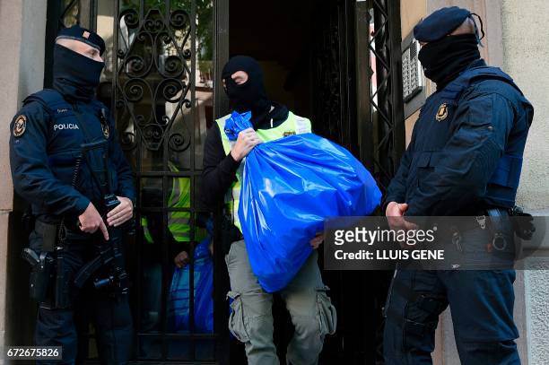 Members of the Catalan Regional Police carries a garbage bag during the raid of a flat in Barcelona on April 25, 2017 that led to the arrest of four...