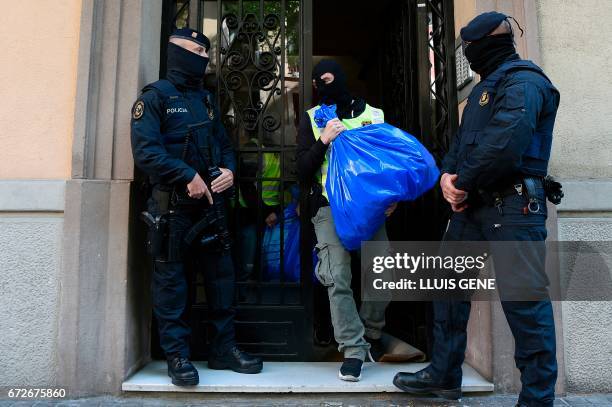 Members of the Catalan Regional Police carries a garbage bag during the raid of a flat in Barcelona on April 25, 2017 that led to the arrest of four...