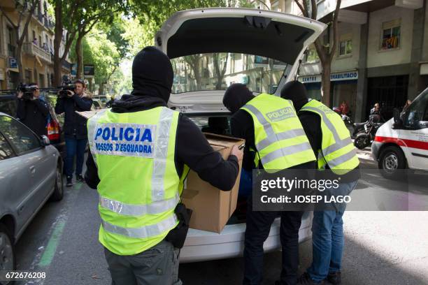 Members of the Catalan Regional Police load a box into a car during the raid of a flat in Barcelona on April 25, 2017 that led to the arrest of four...