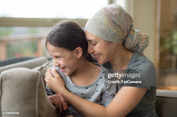 etnische jonge moeder met kanker bedrijf dochter - headscarf home stockfoto's en -beelden