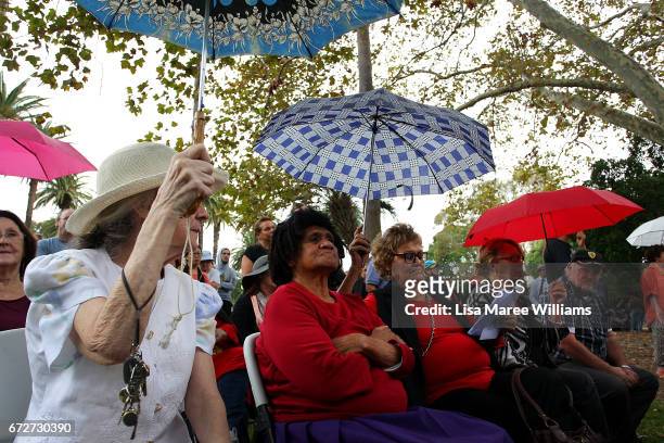 Women take shelter under umbrellas during the ANZAC service at Redfern Park on April 25, 2017 in Sydney, Australia. The annual ANZAC coloured diggers...
