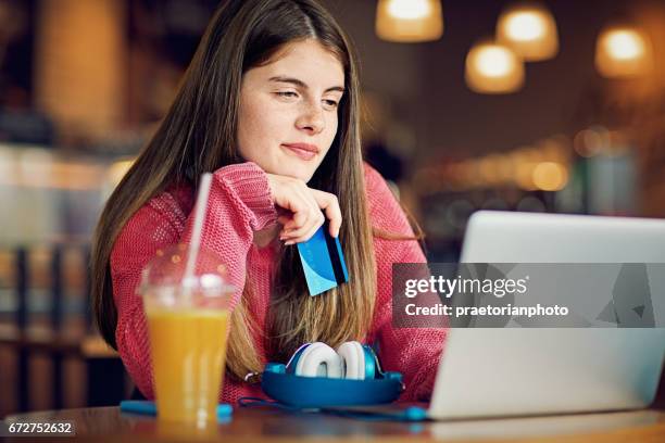 teenage girl is shopping online in a cafeteria - girl after shopping stock pictures, royalty-free photos & images