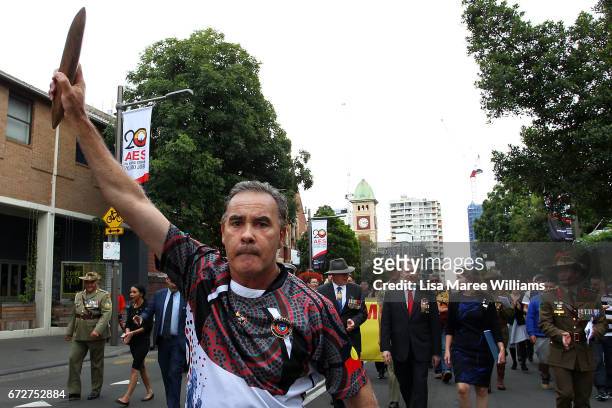 Indigenous man holds a clapstick in the air as he leads the ANZAC march towards Redfern Park on April 25, 2017 in Sydney, Australia. The annual ANZAC...