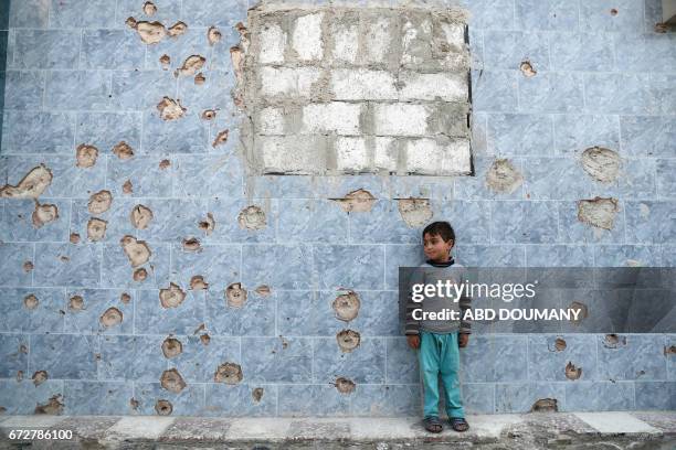 Syrian boy stands against a bullet-riddled wall in the rebel-held town of Douma, on the eastern outskirts of the Syrian capital Damascus, on April...