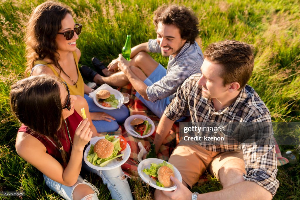 Freunde sitzen in Rasen und Burger am Grill-party