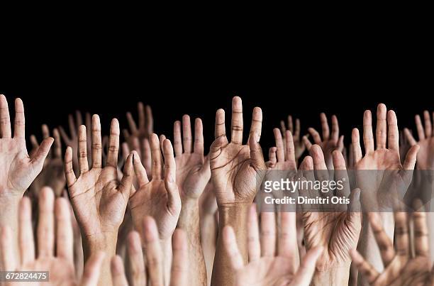 many hands in the air, black background - braccia alzate foto e immagini stock