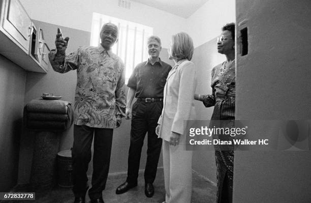 President William Clinton, First Lady Hillary Rodham Clinton, President Nelson Mandela and Graca Machel are photographed in the jail cell where...