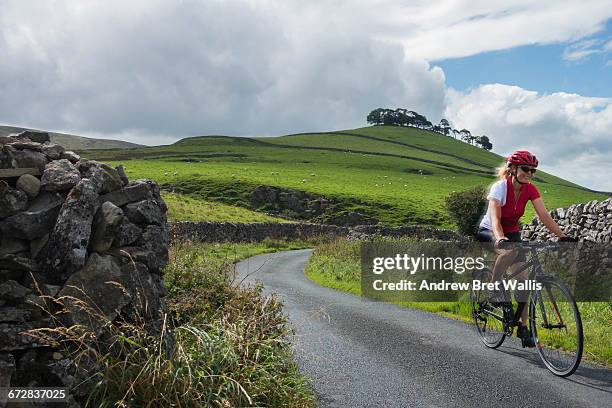 female cyclist riding through the yorkshire dales - yorkshire dales national park stock pictures, royalty-free photos & images