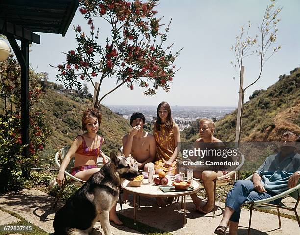 1960s THREE MEN TWO WOMEN WEARING BATHING SUITS SITTING ON PATIO WITH GERMAN SHEPHERD DOG LOS ANGELES HILLS CALIFORNIA USA