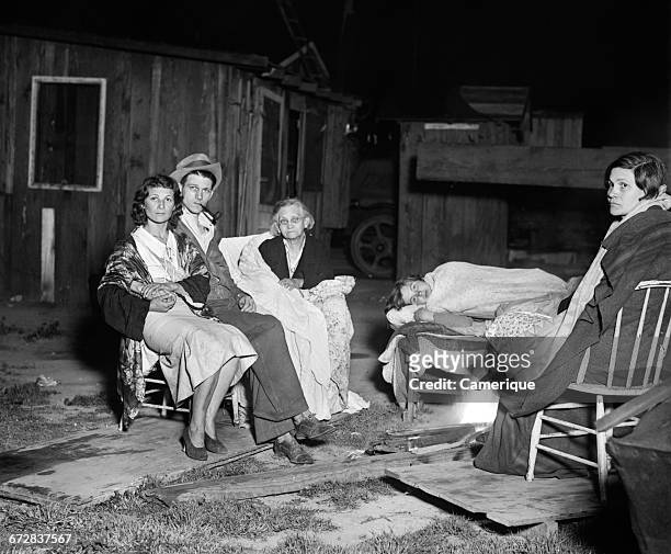 1930s MARCH 10, 1933 EARTHQUAKE AFTERMATH GROUP OF PEOPLE SITTING BY SHACKS AT NIGHT POVERTY LOS ANGELES CALIFORNIA USA