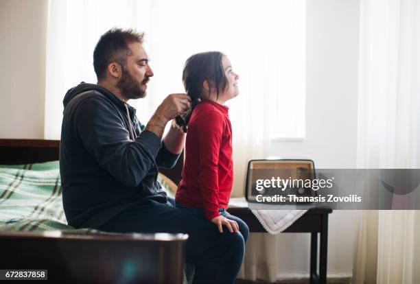 Father styling hair of his daughter at home