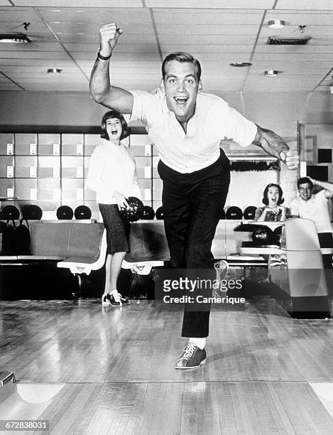 1960s 1950s SMILING MAN SHOWING GOOD FORM IN BOWLING ALLEY