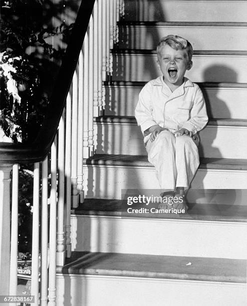 1950s LAUGHING HAPPY LITTLE BOY IN PAJAMAS SITTING ON STAIRS CHRISTMAS MORNING