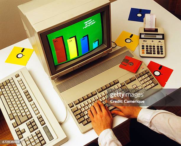 1980s MALE HANDS ON COMPUTER KEYBOARD WITH MONITOR FLOPPY DISKS CALCULATOR