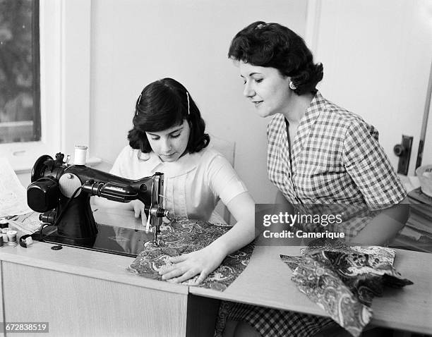 1950s 1960s MOTHER TEACHING DAUGHTER HOW TO SEW USING SEWING MACHINE