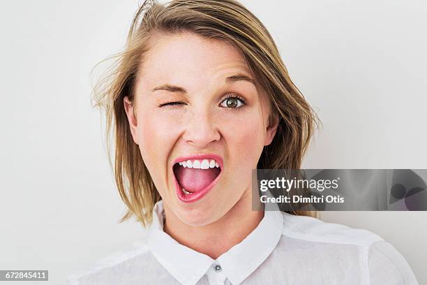 young woman winking with mouth wide open - winking stockfoto's en -beelden