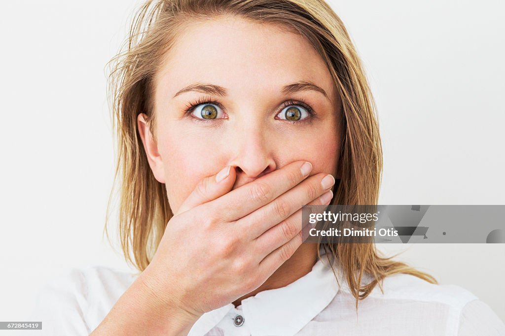 Young woman with hand over her mouth, surprised