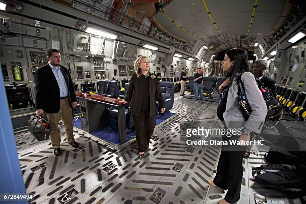 Secretary of State Hillary Rodham Clinton confers with top aides Huma Abedin and Philippe Reines minutes before exiting the plane on October 18, 2011...