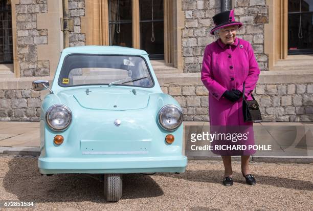 Britain's Queen Elizabeth II stands beside the classic invalid carriage, as she hosts a ceremony to celebrate the 40th Anniversary of Motability, at...