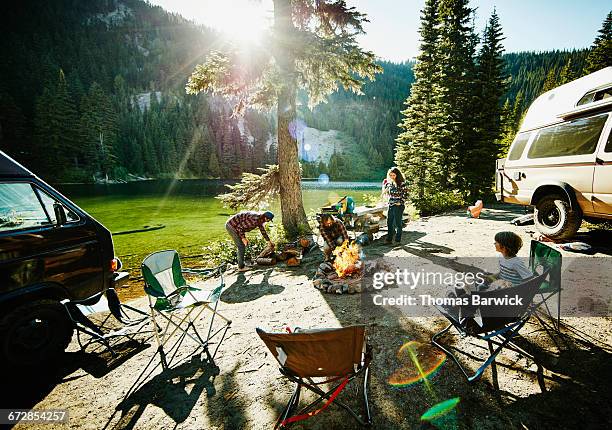 father building fire while family sets up camp - camping family stock pictures, royalty-free photos & images