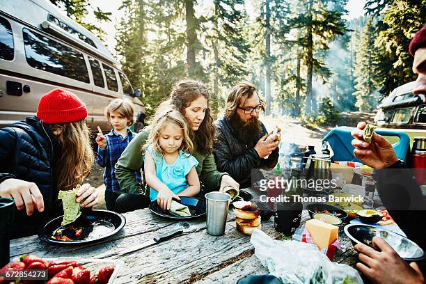 Family and friends eating breakfast while camping