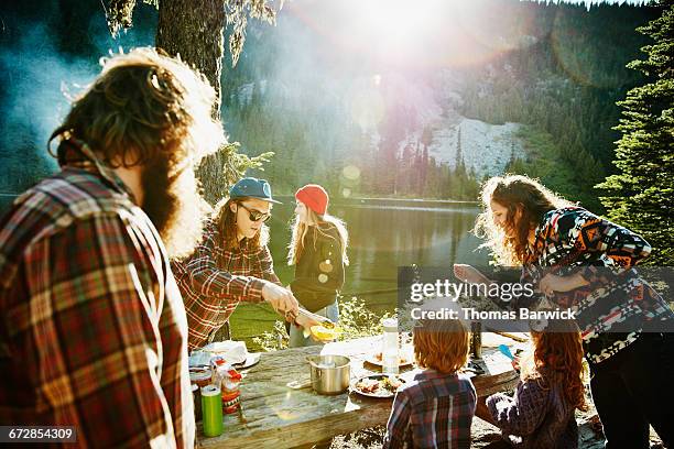 friends and family dishing up dinner while camping - family camping stock-fotos und bilder