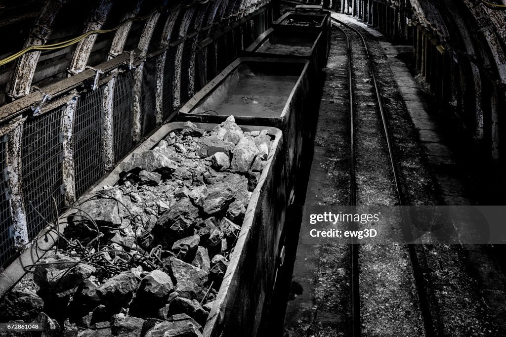 Coal mine underground corridor with railway carriages and hard coal
