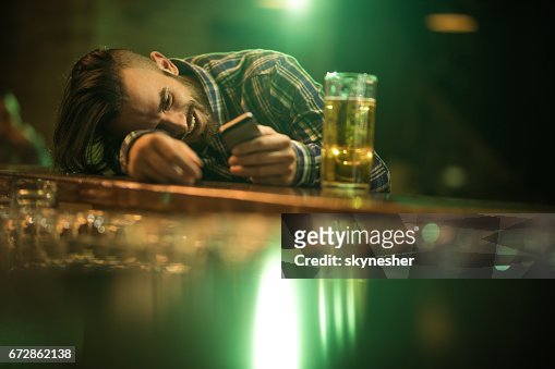 Young Wasted Man Text Messaging On Cell Phone While Leaning On A Bar  Counter High-Res Stock Photo - Getty Images
