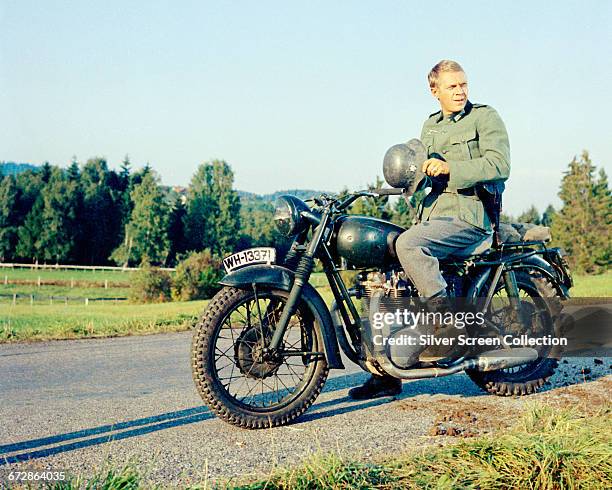 American actor Steve McQueen wearing a German military uniform, sitting astride a Triumph Bonneville motorcycle in a publicity still issued for the...