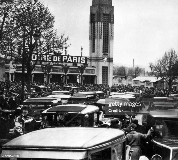 Photo prise dans les années 30 de voitures stationnant devant l'entrée de la Foire de Paris, qui se tient au parc des expositions de la Porte de...