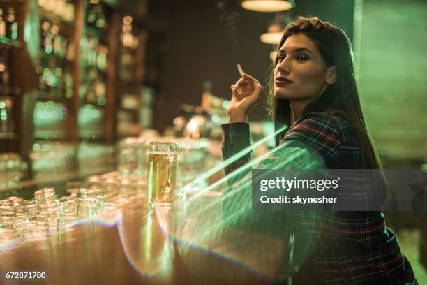 young beautiful woman sitting at bar counter and smoking. - beautiful women smoking cigarettes stock pictures, royalty-free photos & images