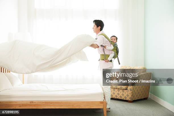 man to housework by carrying a baby - house husband stock pictures, royalty-free photos & images