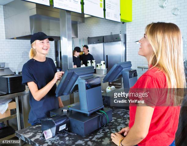 checkout server serving young woman customer ordering at fast food restaurant - pedir imagens e fotografias de stock