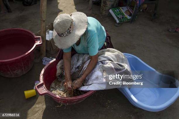 Displaced resident washes clothing in a bin at a temporary housing camp near the destroyed village of Cajamarquilla, Chosica district in Lima, Peru,...