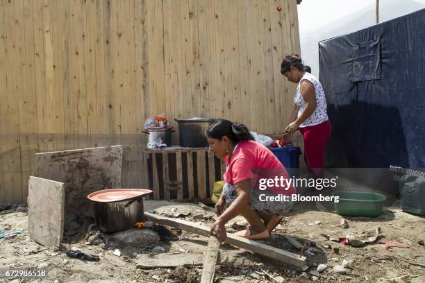 Displaced residents cook outside in a makeshift kitchen at a temporary housing camp near the destroyed village of Carapongo, Chosica district in...