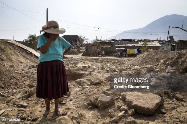 Resident covers her face while standing on the land of her home destroyed by massive floods in the village of Cajamarquilla, Chosica district in...