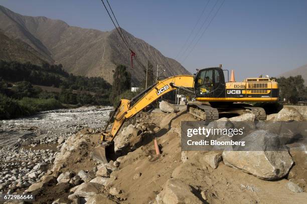 Worker operates a JC Bamford Excavators Ltd. Machine to fix a road destroyed by massive floods in the district of Santa Eulalia, Huarochiri Province,...