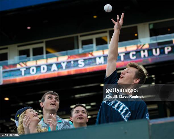 Fan catches a baseball tossed to him by a Seattle Mariners player after warm ups prior to a MLB game against the Detroit Tigers at Comerica Park on...