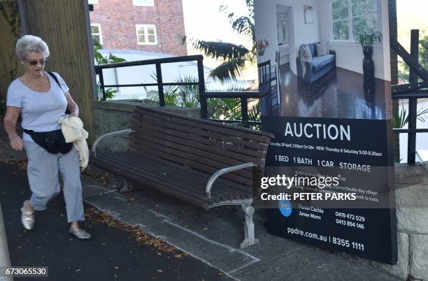 Woman walks past signage for a residential property auction in Sydney on April 26, 2017. Australians are racking up extreme levels of debt to buy...