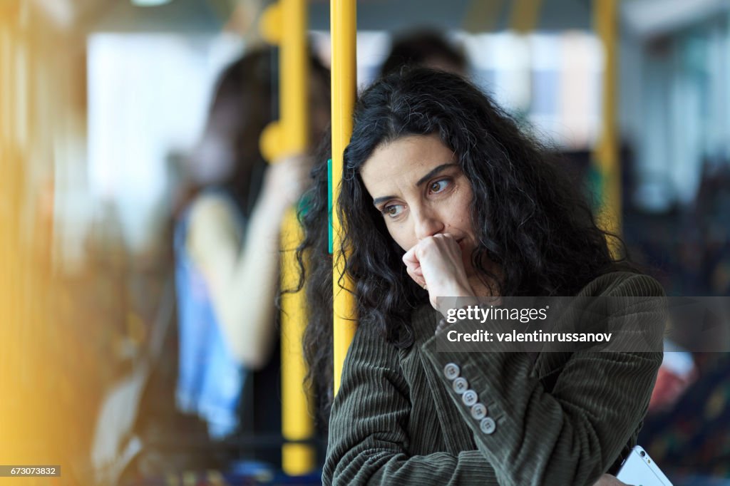 Pensive young woman traveling and holding smart phone
