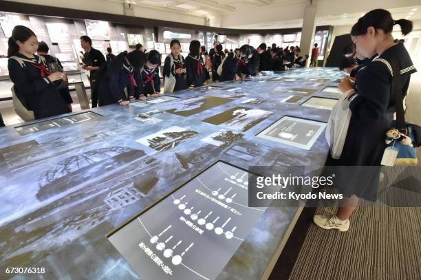 Student visitors observe a display at the east building of the Hiroshima Peace Memorial Museum in the western Japan city on April 26 as the building...