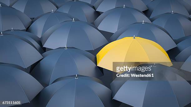 yellow umbrella in between many black umbrellas - joy stock illustrations