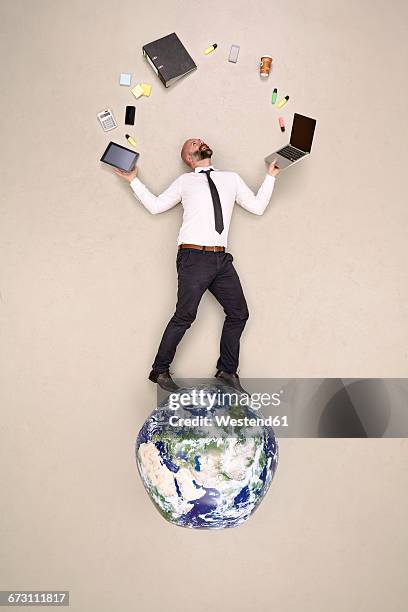 businessman standing on globe juggling with office devices - fare il giocoliere foto e immagini stock