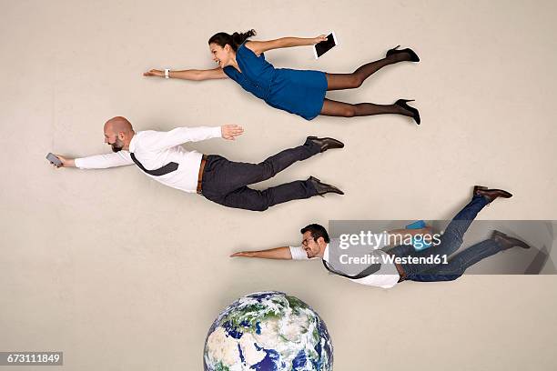 three business colleagues flying above the globe - globe businessman stockfoto's en -beelden