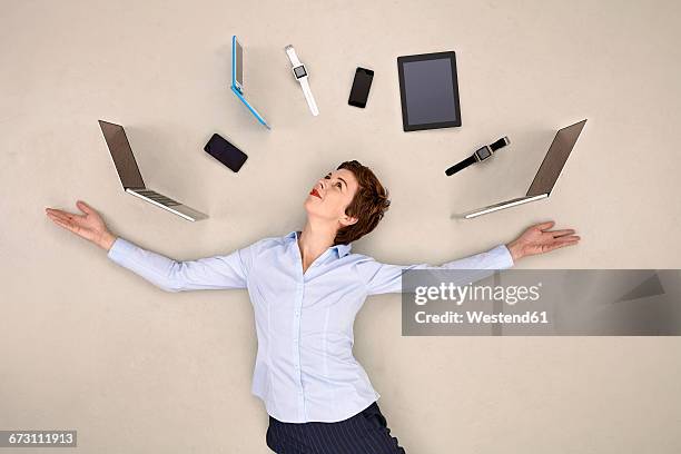 businesswoman juggling mobile devices - polyvalence photos et images de collection